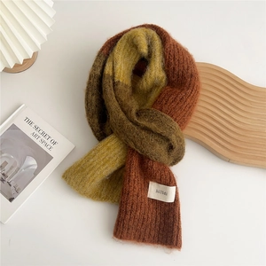 Close-up of tricolor chunky knit scarf with plush wool texture and fabric brand label