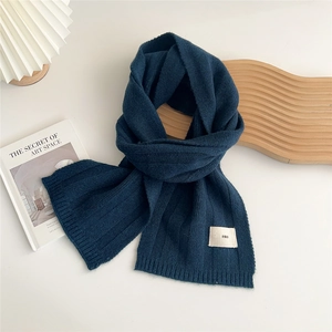 Detail of navy blue knit scarf with vertical stripes and white emo logo patch label