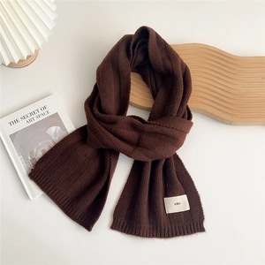 Close-up of dark brown ribbed knit scarf featuring a white emo logo tag on white background