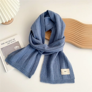 Close-up of navy blue knit scarf with vertical ribbed texture and minimalist emo tag