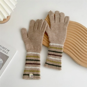 Close-up of light brown knitted gloves with colorful striped cuffs on a wooden board