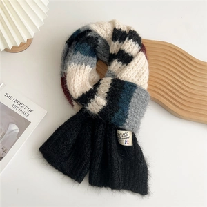 Detailed close-up of thick multi-color patchwork knit scarf with woven brand label
