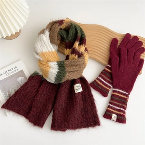 Flat lay of colorful patchwork knit scarf and burgundy gloves on artistic props