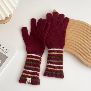 Close-up of burgundy knitted glove with colorful striped cuffs and branded woven label