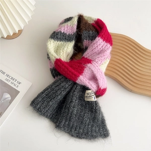 Detail of multi-color chunky knit scarf with white woven label on bright desk