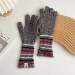 Detail of grey knitted gloves with colorful striped cuffs and soft wool blend texture