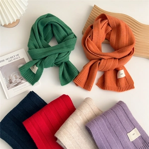 Solid knit scarves in multiple colors with ribbed texture and minimalist woven emo label
