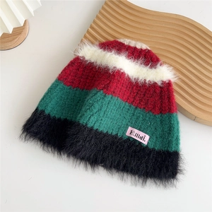 Détail du bonnet en maille rayée avec motifs rouges, verts, noirs et bordure en fausse fourrure