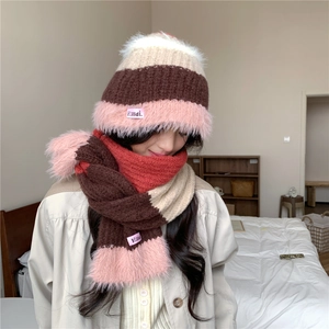 Détail d'un ensemble bonnet et écharpe tricotés avec pompon en fausse fourrure rose et rayures