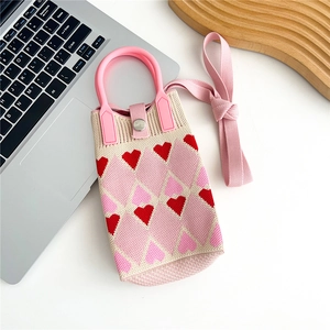 Detail of knitted heart pattern mini phone bag with pink handle and metallic snap button