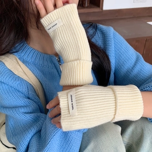 Détail du tricot de gants en laine beige sans doigts avec étiquette Jennie Wool