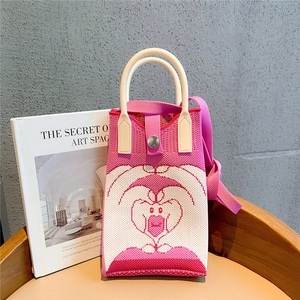 Detail of knitted mini phone bag with white heart pattern and silver buckle closure