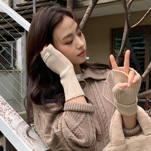 Gros plan de mitaines en tricot beige avec texture côtelée et étiquette de marque en tissu