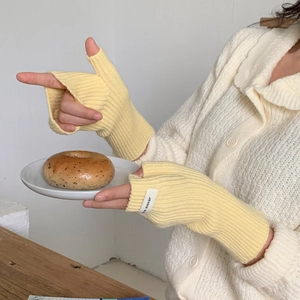 Détail de mitaines en tricot jaune clair avec texture côtelée et trou pour le pouce
