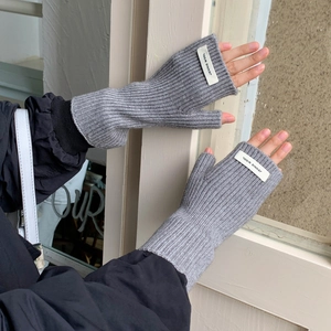 Détail de mitaines en tricot gris avec étiquette Jennie Wool et poignets côtelés