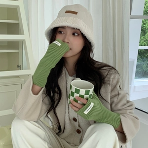Détail des mitaines en tricot vert avec un chapeau bob en peluche de couleur crème
