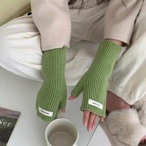 Gros plan sur les mitaines en tricot côtelé vert herbe avec une étiquette en tissu blanc