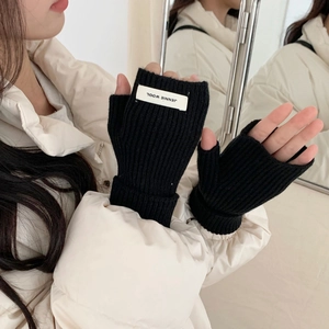 Détail de mitaines en tricot côtelé noir avec une étiquette de design blanche carrée