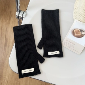 Gros plan détaillé de mitaines en tricot côtelé noir avec une étiquette de marque blanche