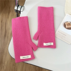 Détail de la maille côtelée des mitaines en laine rose vif avec une étiquette textile