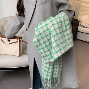 Detail of green and white plaid scarf with fringe tassels worn with a grey coat