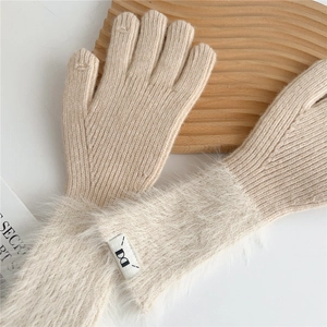 Detailed view of beige knitted gloves with plush faux fur trim and sewn brand label
