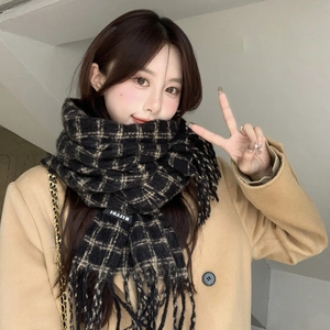 Close-up of black and beige plaid scarf with soft fringe and premium fabric label detail