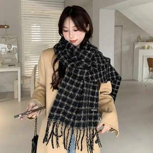 Close-up of a thick black and white plaid scarf featuring soft fringe and brand label