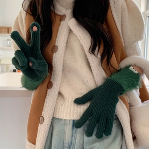 Close-up of green knit thermal gloves with faux fur trim and touchscreen finger openings