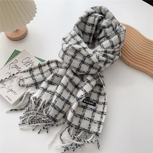 Close-up of black and white checkered scarf with fringe and a sewn-on brand label
