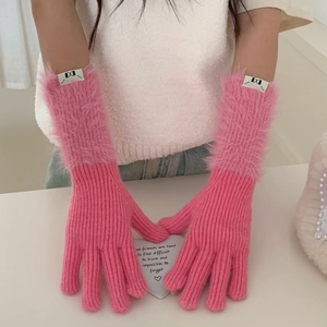 Detail of pink knitted gloves featuring soft faux fur cuffs and a chic woven label