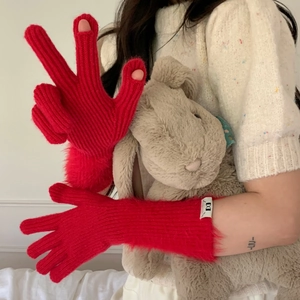 Detail of red cable-knit gloves featuring plush wrist cuffs and finger openings