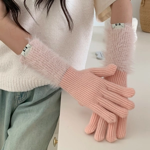 Detail of pink knitted gloves featuring soft faux fur cuffs and decorative label tag