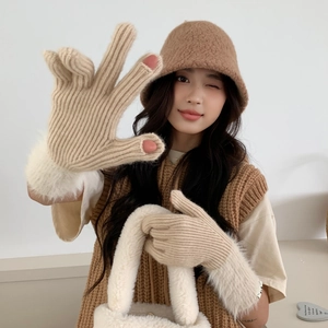 Close-up of beige knitted fingerless gloves with white faux fur trim and cozy winter hat