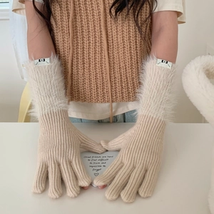 Close-up of beige knitted winter gloves with faux fur cuffs and a decorative label