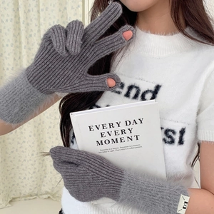 Detail of grey knitted winter gloves featuring plush faux fur cuffs and finger openings