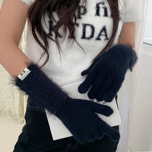 Close-up of knit winter gloves with navy blue faux fur trim and cozy texture