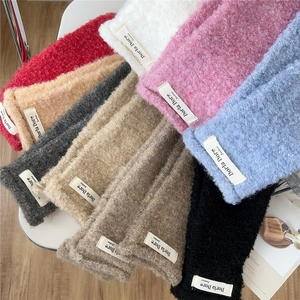 Detail view of colorful curly plush mittens with fashion woven labels in diverse colors