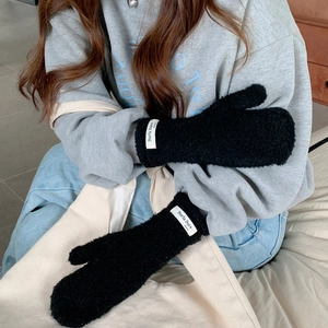 Detail of black plush mittens showing the high-density fleece texture and woven logo tag