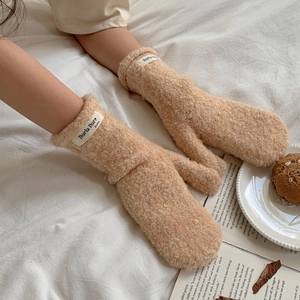 Detailed texture of beige teddy plush mittens with fashion label on the wrist band