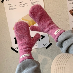 Close-up of pink fuzzy mittens featuring a soft texture and branded woven wrist label