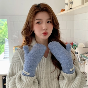 Detail of blue faux shearling mittens with woven label worn by a female model