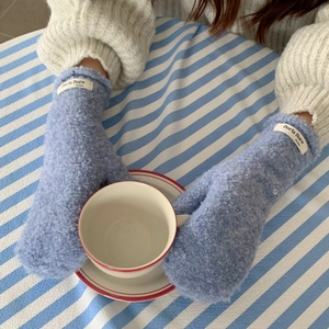 Detail of light blue fuzzy mittens with textured pile fabric and branded woven label
