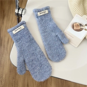 Detailed close-up of light blue plush mittens featuring a woven brand label and soft texture