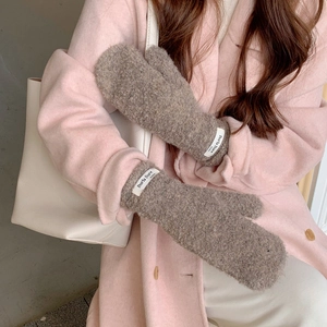 Close-up of thick coffee brown plush mittens with a white woven brand label