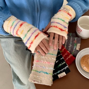 Close-up of knitted fingerless gloves with colorful striped fringe and brand label detail