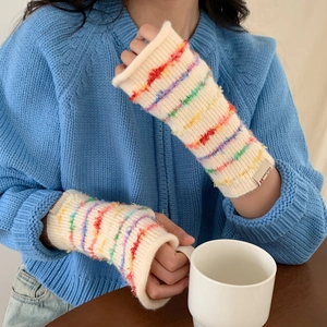 Close-up of cream knitted arm warmer with colorful rainbow stripes and sewn label