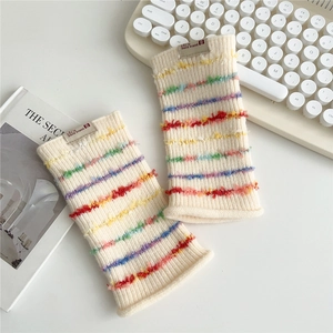 Close-up of knit fingerless gloves with colorful 3D fringe stripes on cream base