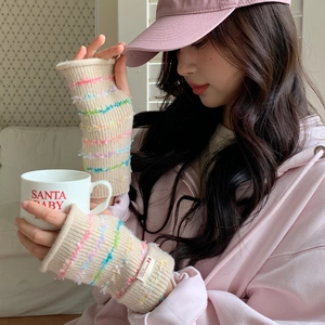 Close-up of cream knit arm warmers with colorful fringe stripes and fingerless design
