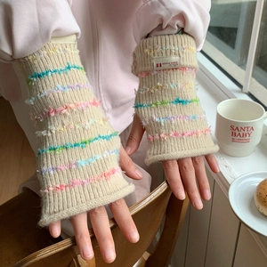 Close-up of beige knitted fingerless gloves with colorful rainbow fringe details